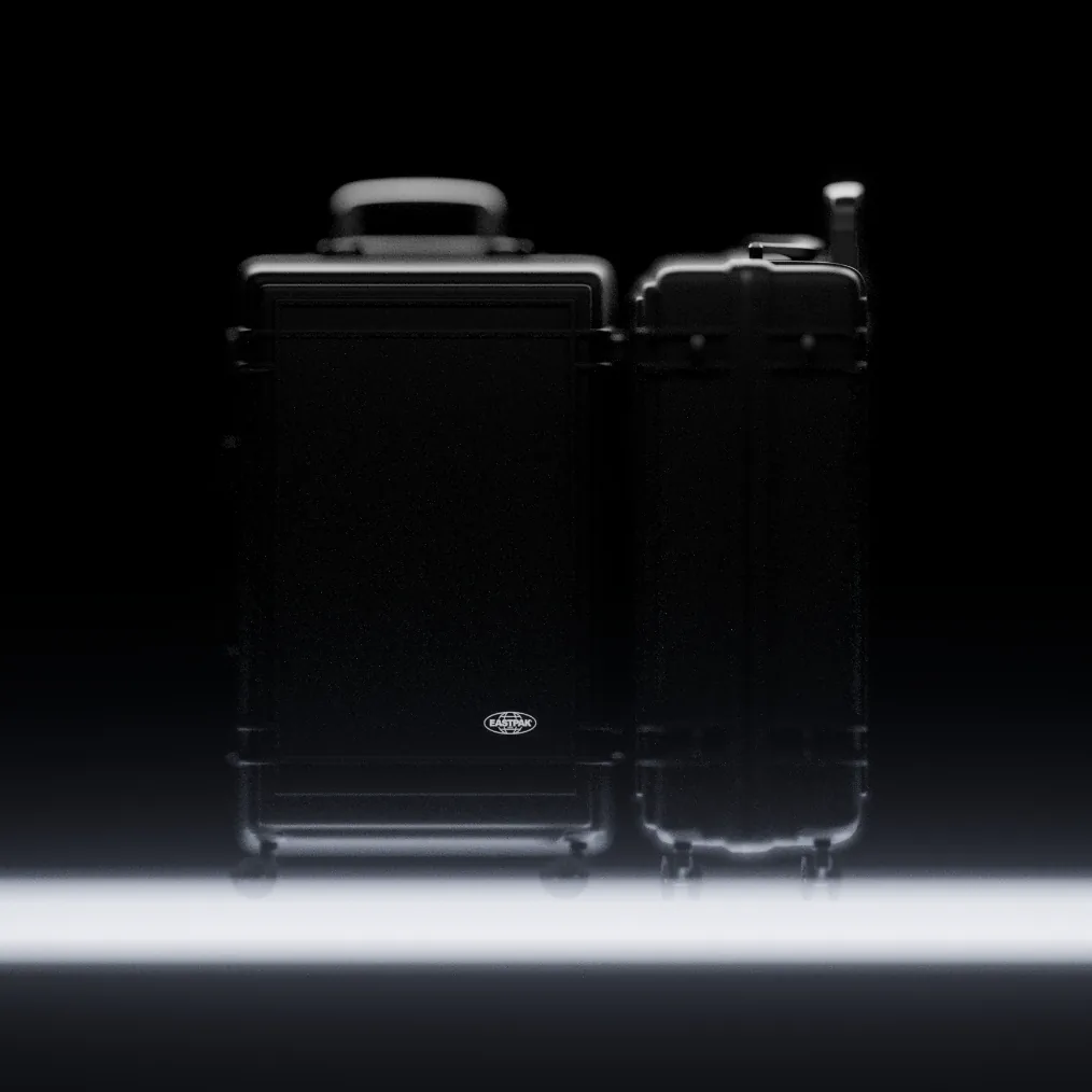 Two Eastpak Resist'r hard-shell suitcases standing side by side, lit from below